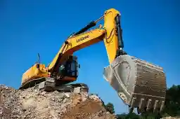 Yellow excavator digging against a blue sky
